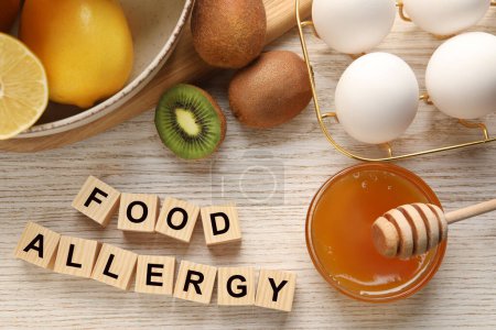 Alergia alimentaria. Diferentes productos frescos y cubos en mesa de madera clara, puesta plana