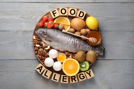Alergia alimentaria. Diferentes productos frescos y cubos en mesa de madera gris, vista superior