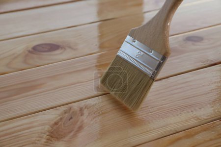 Varnishing wooden surface with brush, closeup view