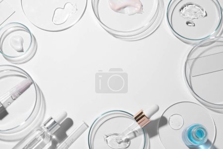 Photo for Frame made of petri dishes, samples of cosmetic serums, bottles and pipettes on white background, flat lay. Space for text - Royalty Free Image