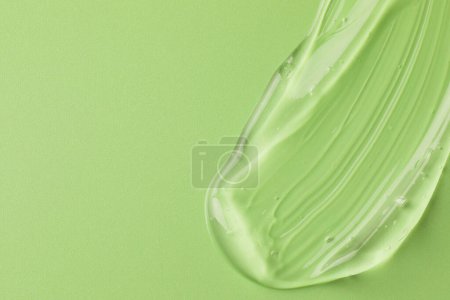 Photo for Smear of clear cosmetic gel on light green background, top view. Space for text - Royalty Free Image