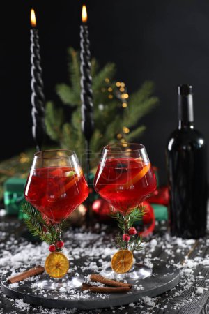 Téléchargez les photos : Cocktail de Noël Sangria dans des verres, bougies allumées et neige sur table en bois sombre - en image libre de droit