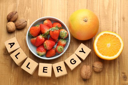 Alergia alimentaria. Nueces, fresas, cítricos y cubos sobre mesa de madera, puesta plana