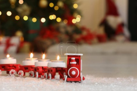 Téléchargez les photos : Train de jouets avec des bougies allumées près de l'arbre de Noël dans la chambre, gros plan. Espace pour le texte - en image libre de droit