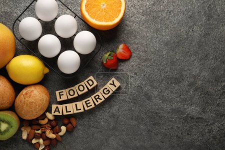 Alergia alimentaria. Diferentes productos frescos y cubos de madera sobre mesa gris, plano con espacio para el texto