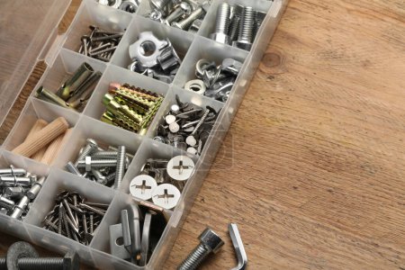 Photo for Organizer with many different fasteners on wooden table, above view. Space for text - Royalty Free Image