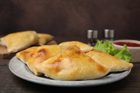 Foto de Deliciosas samosas y lechuga sobre mesa de madera - Imagen libre de derechos