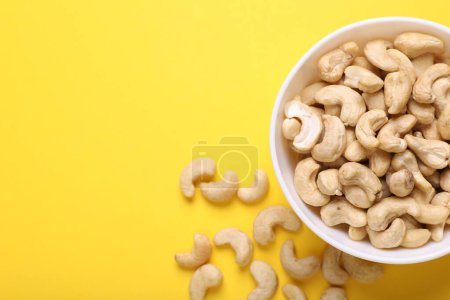 Tasty cashew nuts on yellow background, top view. Space for text
