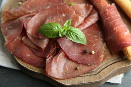 Photo for Delicious bresaola and basil leaves on grey table, closeup - Royalty Free Image