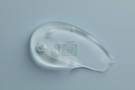 Photo for Smear of clear cosmetic gel on light blue background, top view - Royalty Free Image