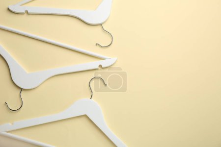 Photo for White hangers on pale yellow background, flat lay. Space for text - Royalty Free Image