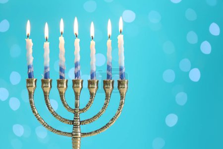 Téléchargez les photos : Hanoukka fête. Menorah avec des bougies allumées sur fond bleu clair avec des lumières floues, espace pour le texte - en image libre de droit
