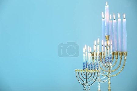 Téléchargez les photos : Hanoukka fête. Menorahs avec des bougies allumées sur fond bleu clair, espace pour le texte - en image libre de droit