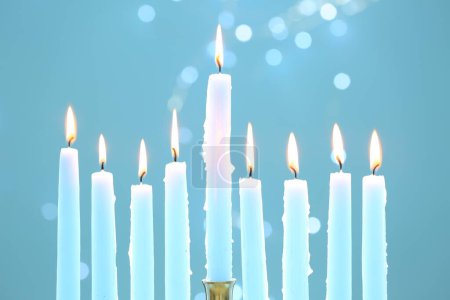Téléchargez les photos : Hanoukka fête. Brûler des bougies sur fond bleu clair avec des lumières floues, gros plan - en image libre de droit