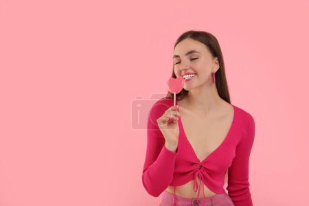 Pink look. Beautiful woman with lollipop on color background, space for text