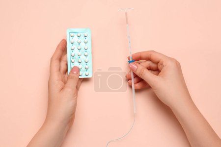 Mujer con píldoras anticonceptivas y dispositivo intrauterino sobre fondo beige, vista superior. Elegir el método anticonceptivo
