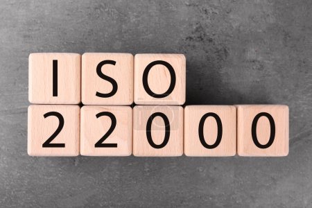Cubes en bois avec abréviation ISO et numéro 22000 sur table texturée grise, plat