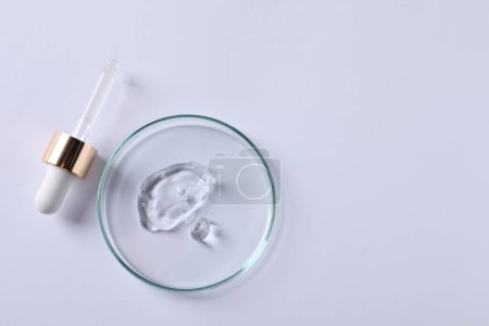 Photo for Petri dish with cosmetic serum and pipette on white background, top view. Space for text - Royalty Free Image