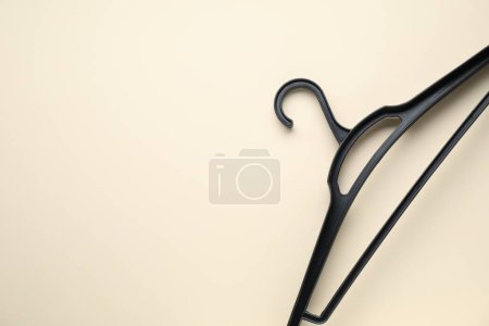 Photo for Empty black hanger on beige background, top view. Space for text - Royalty Free Image