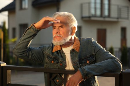Téléchargez les photos : Concept de vie privée. Curieux homme âgé espionnant les voisins au-dessus de la clôture à l'extérieur - en image libre de droit