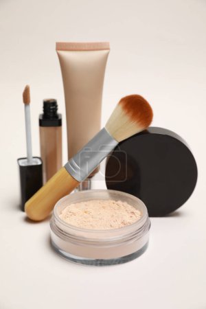 Loose face powder and other makeup products on light background, closeup