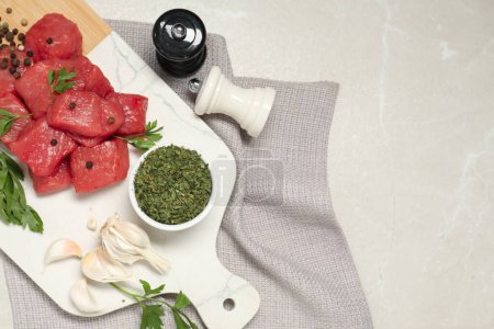 Raw beef meat and different ingredients for cooking delicious goulash on light grey marble table, flat lay. Space for text