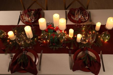 Christmas table setting with burning candles and festive decor, above view