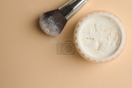 Rice loose face powder and makeup brush on beige background, flat lay. Space for text