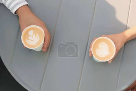 Téléchargez les photos : Café à emporter. Couple avec gobelets en papier à table grise, vue ci-dessus - en image libre de droit