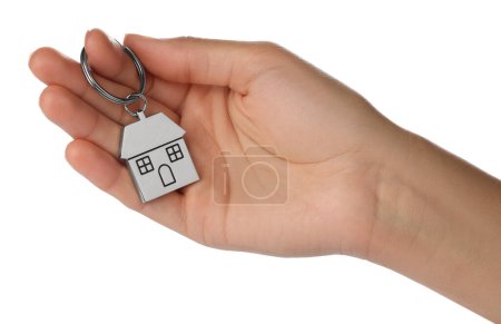 Woman holding metallic keychain in shape of house on white background, closeup
