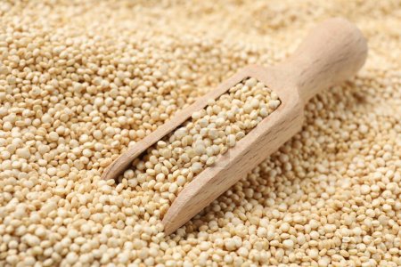 Photo for Wooden scoop and raw quinoa as background, closeup - Royalty Free Image