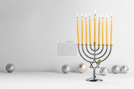 Téléchargez les photos : Hanoukka fête. Menorah avec des bougies allumées et des ornements de vacances sur une table en bois blanc, espace pour le texte - en image libre de droit
