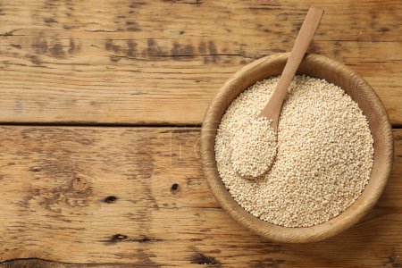 Sec graines de quinoa et cuillère dans un bol sur une table en bois, vue sur le dessus. Espace pour le texte