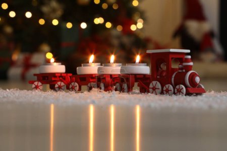Téléchargez les photos : Train de jouets avec des bougies allumées près de l'arbre de Noël dans la chambre, gros plan - en image libre de droit