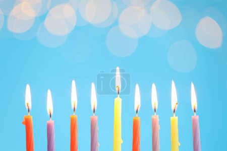 Téléchargez les photos : Hanoukka fête. Brûler des bougies sur fond bleu clair avec des lumières floues, espace pour le texte - en image libre de droit