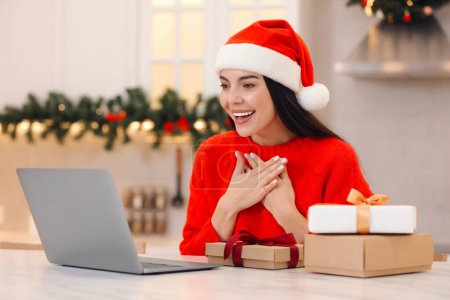 Weihnachten online feiern und Geschenke per Post austauschen. Lächelnde Frau bedankt sich bei Videoanruf zu Hause für Geschenk