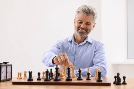 Hombre feliz jugando ajedrez durante el torneo en la mesa en el interior