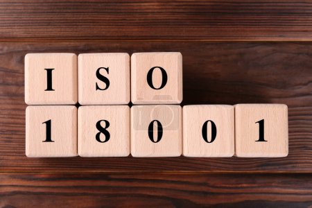 Cubes with abbreviation ISO and number 18001 on wooden table, flat lay