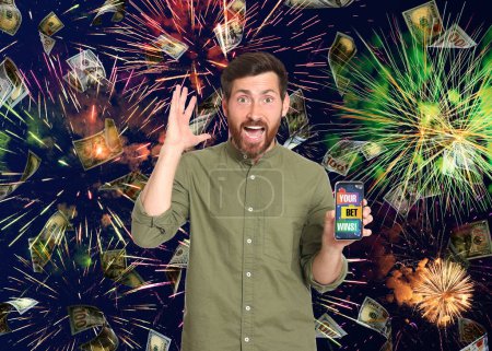 Your Bet Wins! Emotional man holding smartphone under money shower against background with fireworks