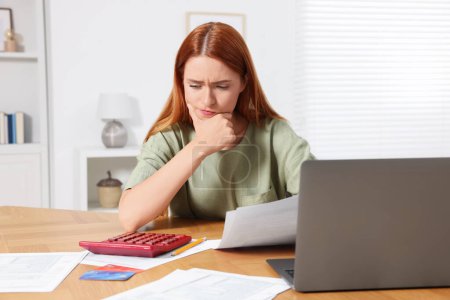Téléchargez les photos : Femme calculant les taxes à table dans la chambre - en image libre de droit