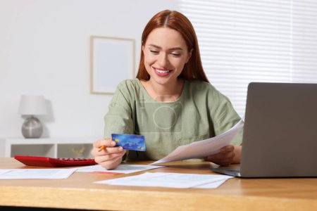 Foto de Mujer con tarjeta de crédito utilizando el ordenador portátil para pagar impuestos en línea en casa - Imagen libre de derechos