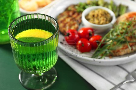 Delicious drink with tarragon in glass on green table, closeup. Space for text