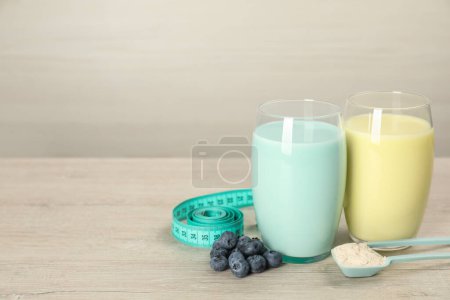 Tasty shakes with blueberries, measuring tape and powder on wooden table, space for text. Weight loss
