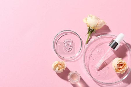 Photo for Bottle of cosmetic serum, flowers and petri dishes with samples on pink background, flat lay. Space for text - Royalty Free Image
