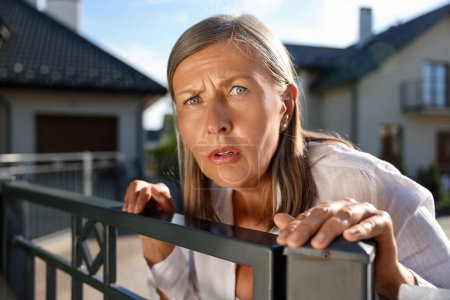 Konzept des Privatlebens. Neugierige Seniorin spioniert Nachbarn über Gartenzaun aus