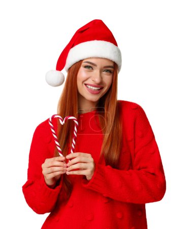 Foto de Mujer joven en suéter rojo y sombrero de Santa con bastones de caramelo sobre fondo blanco. Celebración de Navidad - Imagen libre de derechos