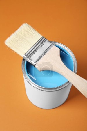 Canette de peinture bleu clair avec pinceau sur fond orange pâle, vue ci-dessus