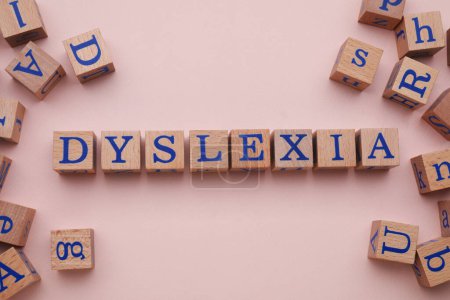 Wooden cubes with word Dyslexia on beige background, flat lay
