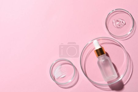 Photo for Bottle of cosmetic serum and petri dishes with samples on pink background, flat lay. Space for text - Royalty Free Image