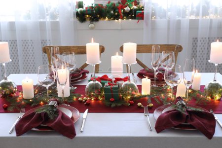 Christmas table setting with burning candles and festive decor